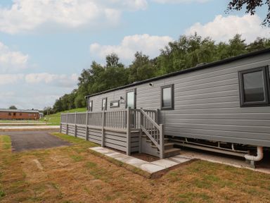 A mobile home with steps and a deck in an outdoor area at The Pines 2 Bedrooms Delamere