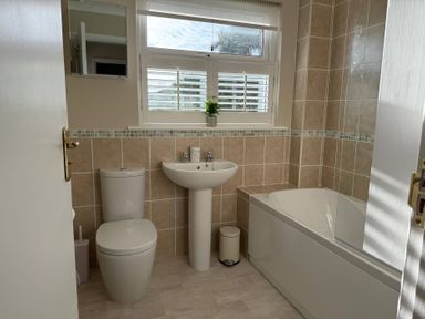 A bathroom with a sink, toilet, bathtub, and mirror at 42 Little Trelyn in Rock