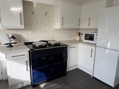 A kitchen with a blue cooker and microwave at 42 Little Trelyn Rock