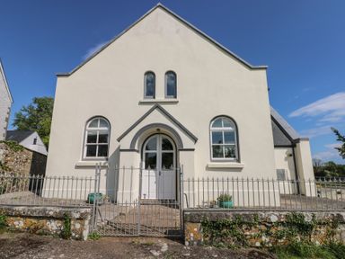 A white building with arched windows and a gate in front at Zoar Chapel in Carew