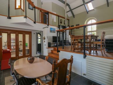 A split-level room with dining tables and chairs wooden railing and a staircase at Zoar Chapel in Carew