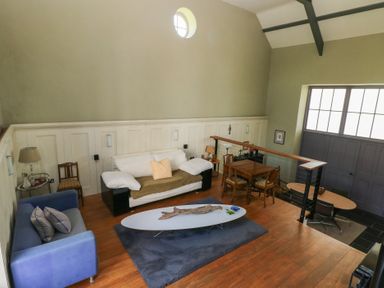 A two-level room with couches a coffee table a dining table and chairs a lamp and large windows at Zoar Chapel in Carew