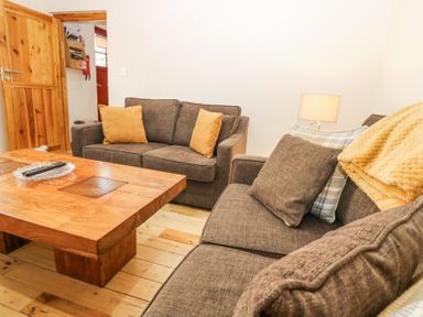 A living room with brown sofas wooden coffee table and a lamp at Smiddy Bothy in Edzell