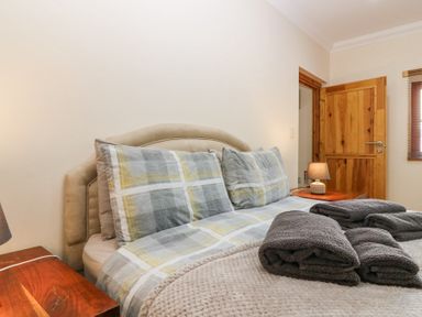 A bedroom with a bed made with patterned bedding and folded towels on top at Smiddy Bothy in Edzell
