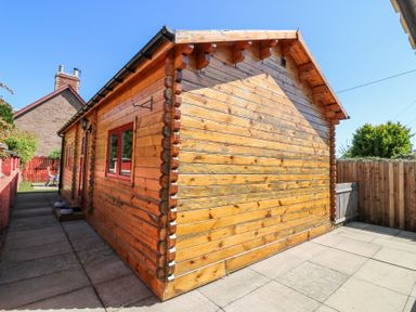 A wooden cabin with windows and a small patio area at Smiddy Bothy in Edzell