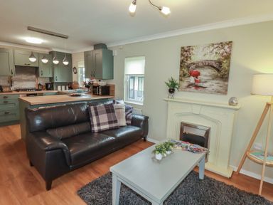 A living room with a sofa, coffee table, and kitchen area at Lodge 9 - Lamorna Tregolds near St Merryn