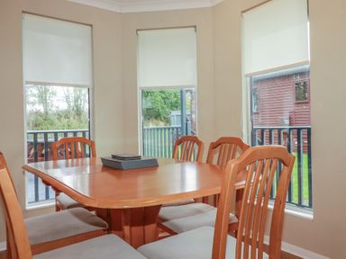 A dining room with a wooden table and chairs at Lodge 9 - Lamorna in Tregolds near St Merryn