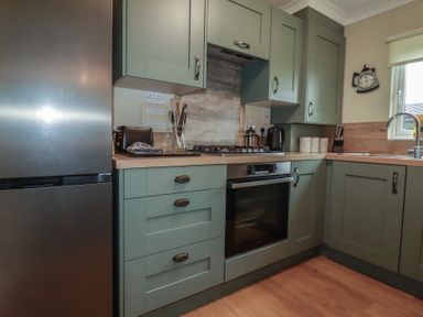 A kitchen with appliances and storage cabinets at Lodge 9 - Lamorna Tregolds near St Merryn