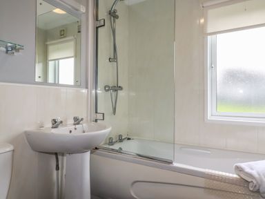 A bathroom with a bathtub, sink, and toilet at Lodge 9 - Lamorna Tregolds near St Merryn