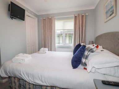 A bedroom with a bed and television at Lodge 9 - Lamorna Tregolds near St Merryn