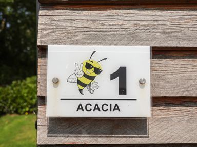 A sign featuring a bee illustration and the number 1 at Honeypot Hideaways - Acacia