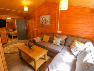 A living room with a sofa and coffee table at Stumps Cross Lodge Upper Coscombe near Winchcombe