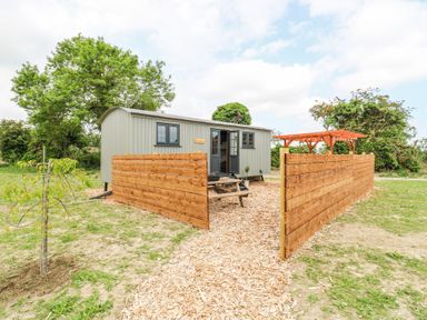 A small shed like building with wooden fencing and a picnic table outside at Woodpecker in Lode near Bottisham