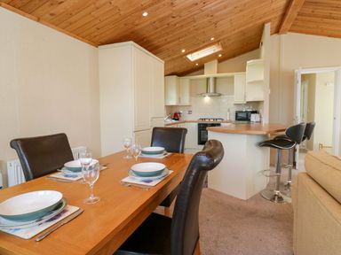 A dining room with a table and kitchen area at Wansfell 2 Limefitt Park near Troutbeck