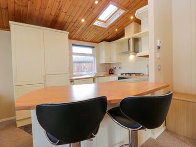 A kitchen with bar stools and cabinets at Wansfell 2 in Limefitt Park near Troutbeck