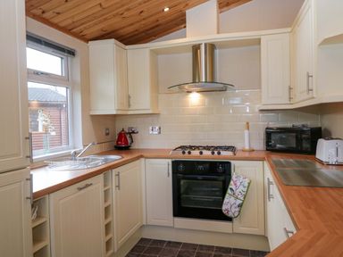 A kitchen with cabinets, cooking range, sink, and microwave at Wansfell 2 in Limefitt Park near Troutbeck