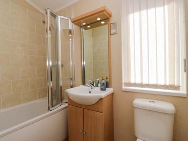 A bathroom with a bathtub, shower, sink, and toilet at Wansfell 2 Limefitt Park near Troutbeck