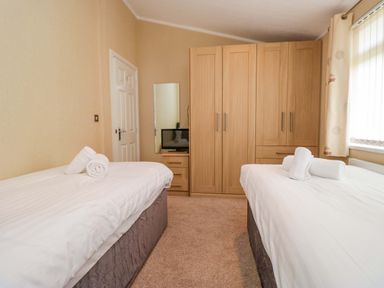 A bedroom with two beds and a wardrobe at Wansfell 2 in Limefitt Park near Troutbeck