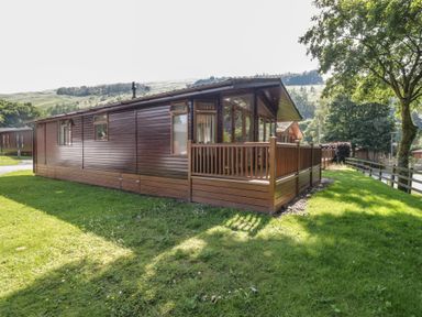 A holiday home with wooden exterior and deck at Wally's Folly in Limefitt Park near Troutbeck