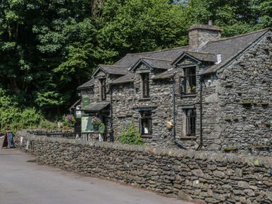A stone building with windows and flower pots at Wally's Folly in Limefitt Park near Troutbeck