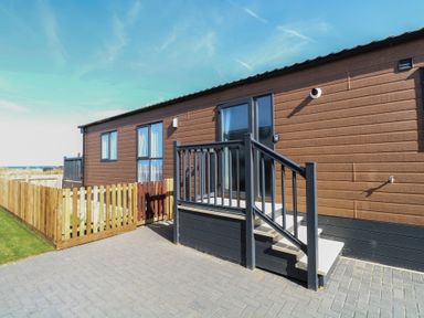 A mobile home with steps and a fence at Sand & Serenity in Bacton