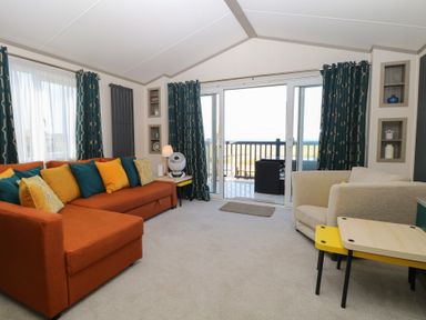 A living room with a sofa and sliding door at Sand & Serenity in Bacton