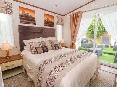 A bedroom with a bed and window leading outside at Ty Seren in New Quay