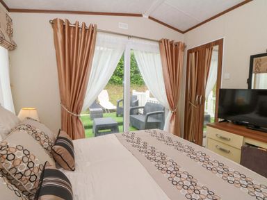 A bedroom with a bed and a television at Ty Seren in New Quay