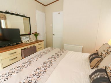 A bedroom with a bed and television at Ty Seren in New Quay
