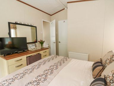 A bedroom with a bed and television at Ty Seren in New Quay