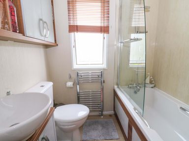 A bathroom featuring a sink, toilet, bathtub, and shower at Ty Seren in New Quay