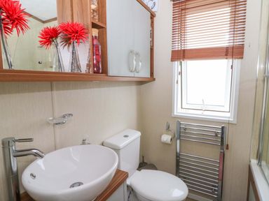 A bathroom with a sink, toilet, and mirror at Ty Seren in New Quay