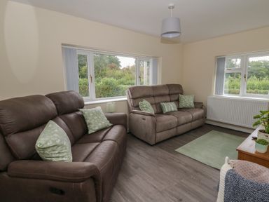 A living room with recliner sofas and a coffee table at Glandwr House in Crossgates near Llandrindod Wells