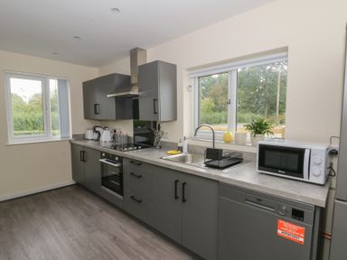 A kitchen with sink, oven, microwave and windows at Glandwr House Crossgates near Llandrindod Wells