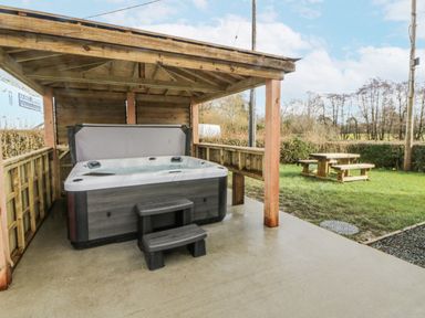 A hot tub under a wooden shelter in an outdoor area at Glandwr House Crossgates near Llandrindod Wells