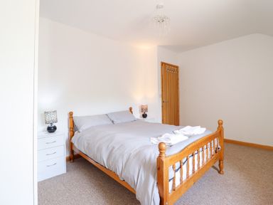 A bedroom with a wooden bed and nightstands at Gwernffridd