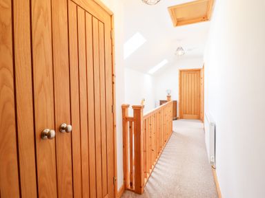 A hallway with wooden doors and a railing at Gwernffridd