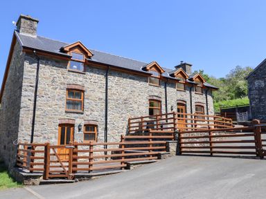 A stone house with a driveway and wooden railings at Gwernffridd Pennant near Llanbrynmair