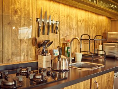 A kitchen counter with a stove a kettle a sink knives utensils and dish rack at Russet Lodge in Glastonbury