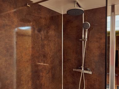 A shower with two showerheads and brown textured walls at Russet Lodge in Glastonbury