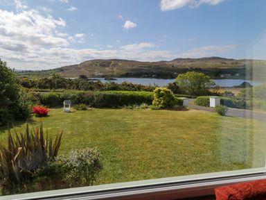 A grassy garden with shrubs and a lake with hills in the background at LOCH ILLION VIEW in Dungloe County Donegal
