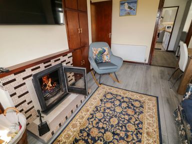 A room with a fireplace and a rocking chair with a peacock cushion at LOCH ILLION VIEW in Dungloe County Donegal
