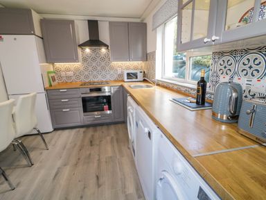 A kitchen with grey cabinets white appliances wooden countertops and patterned tile backsplash at LOCH ILLION VIEW in Dungloe County Donegal