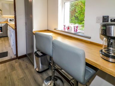 A kitchen counter with two stools a coffee maker and a window with tea set at LOCH ILLION VIEW in Dungloe County Donegal