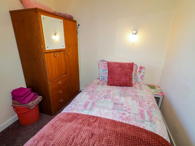 A bedroom with a single bed a wooden wardrobe folded towels and a small side table at LOCH ILLION VIEW in Dungloe County Donegal