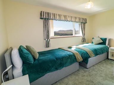 A bedroom with two single beds beside a window with striped curtains at LOCH ILLION VIEW in Dungloe County Donegal