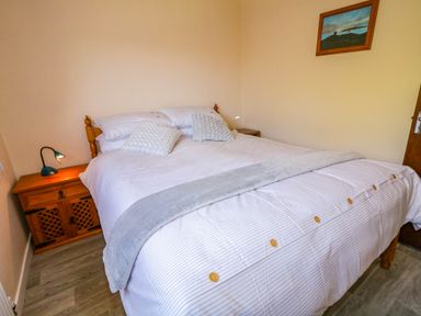 A bedroom with a bed two bedside tables with lamps and a painting on the wall at LOCH ILLION VIEW in Dungloe County Donegal