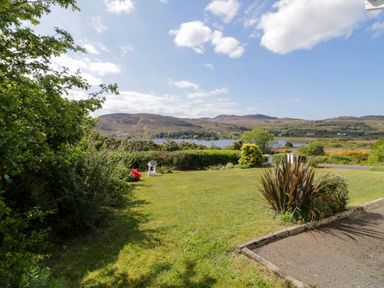A garden with grass shrubs and a lake with mountains in the background at LOCH ILLION VIEW in Dungloe County Donegal