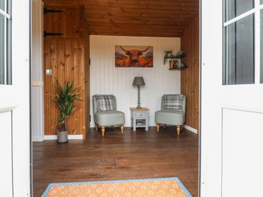 A seating area with two chairs a small table and a lamp a plant and a painting on the wall at The Heron in Lode near Bottisham