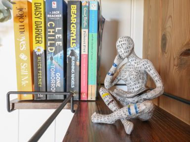 A wooden shelf with several books and a small figurine of a person reading at The Heron in Lode near Bottisham